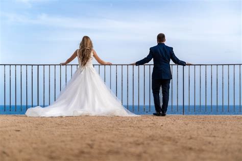 A Bride And Groom Looking Out Over The Ocean With Text That Reads Top