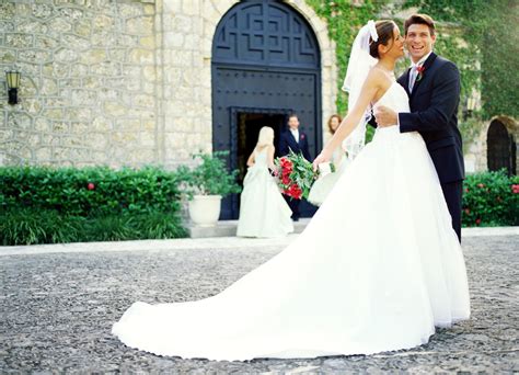 A Bride And Groom Standing In Front Of A Church