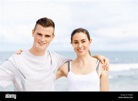 A Couple Standing Next To Each Other On Top Of A Beach