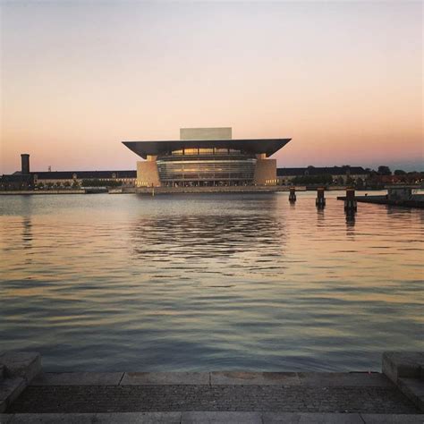 A Large Building Sitting On Top Of A Body Of Water Next To A Boat In