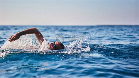 A Person Swimming In The Ocean With A Boat In The Backgroung And Clear