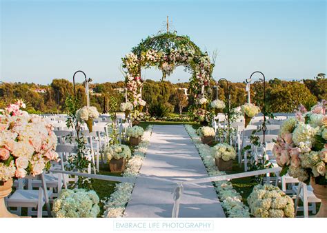 An Outdoor Wedding Ceremony Setup With Chairs And Flowers On The Beach