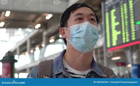 Asian Male Traveler Wearing A Face Mask Waiting For Boarding Airplane