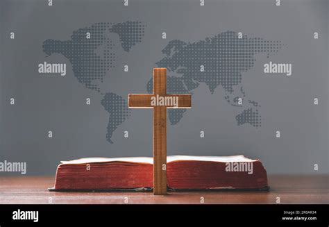 Cross With Open Holy Bible On Table With World Map Blur Background