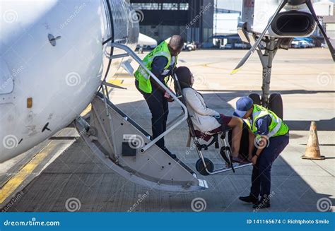 Disabled Passenger Being Helped To Board Aircraft Stock Photo