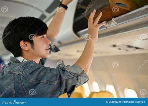 Handsome Asian Male Passenger Putting His Carry On Baggage Into An