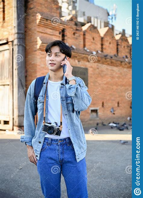 Handsome Asian Male Traveler Talking On The Phone While Standing At Tha