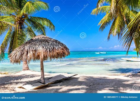 Straw Umbrella On The Tropical Beach With White Sand Ocean And Palms