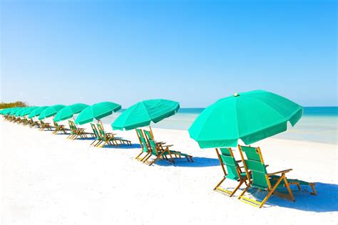 The Beach Is Lined With Umbrellas And Lounge Chairs For People To Sit In It