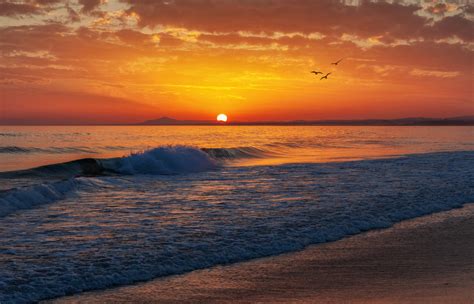 The Sun Is Setting At The Beach With Waves Coming In To Shore And